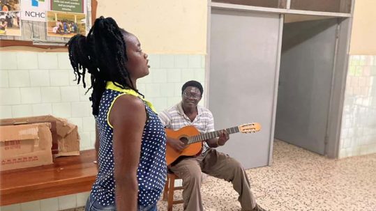Una paciente canta y baila con el acompañamiento a la guitarra del terapeuta